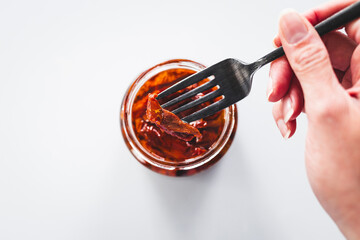 pickled sundried tomatoes in clear glass jar shot from above, pantry staple ingredients