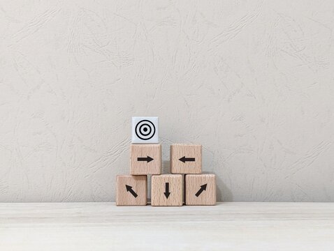 wooden cube and arrows of different directions with the aim of the goal icon. business finance