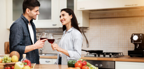 Happy Loving Family. Lovely couple drinking wine together in kitchen at home and cooking healthy...