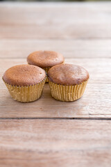three chocolate cupcake on a wooden surface.