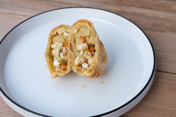 Indonesian pastel sliced open, revealing a warm filling of egg, potato, carrot, and glass noodles—evoking homestyle comfort on a simple white plate
