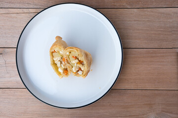 Indonesian pastel sliced open, revealing a warm filling of egg, potato, carrot, and glass noodles—evoking homestyle comfort on a simple white plate