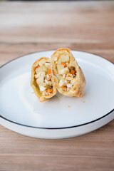 Indonesian pastel sliced open, revealing a warm filling of egg, potato, carrot, and glass noodles—evoking homestyle comfort on a simple white plate