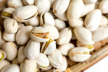 A detailed close-up view of several pistachio nuts in their shells, with some shells partially open, showcasing the nut inside. The intricate textures and natural appearance of the pistachios are high