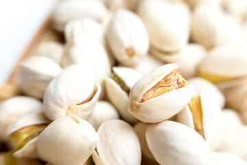 A detailed close-up view of several pistachio nuts in their shells, with some shells partially open, showcasing the nut inside. The intricate textures and natural appearance of the pistachios are high