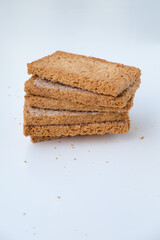 Stack of dried chocolate bagelan bread with sugar sprinkled on top, set against a white background. Bagelan is a crispy, sweet Indonesian snack enjoyed with tea or coffee