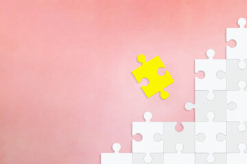 白色の段になったパズルから黄色い1つのピースがとれたピンク色の背景