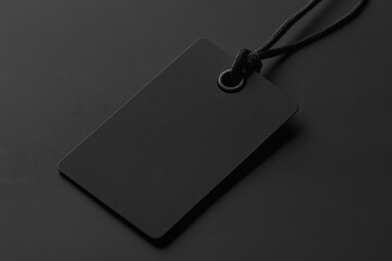 Fototapeta premium A black tag with a black chain hanging from it. The tag is empty and has no writing on it
