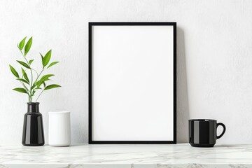 A minimalistic setup featuring a blank frame, a white vase, and a black mug on a marble countertop.