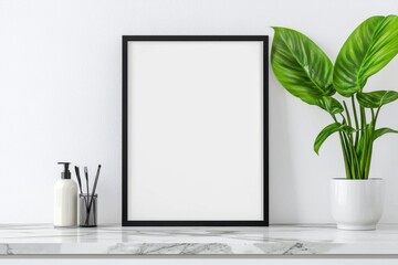 Minimalist interior with a blank frame, green plant, and elegant decor on a marble tabletop.