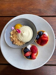 Berry fruit tarts and mascarpone cheesecake served on the white plate on the wooden table 