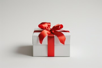 Fototapeta premium A white box with a red ribbon on top. The box is empty and ready to be opened