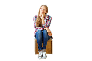 Fototapeta premium Young woman in casual attire sits on wooden box, thoughtful expression, isolated on white background. Concept of contemplation