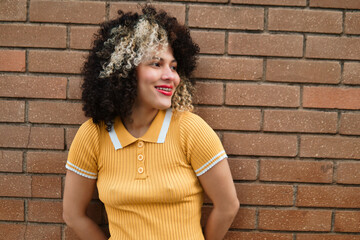 Beautiful Latina woman with braces and afro hair, enjoying and smiling with confidence, on a sunny day outdoors. Lots of joy and positivity