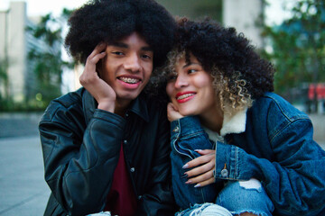 Couple of Latino friends with braces and afro hair enjoying a day at dusk, holding hands on a date, sharing. Lots of joy, laughter and friendship.