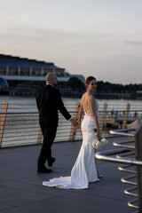Bride holds grooms hand walking across the street