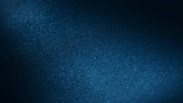 Shifting sand particles under blue light in abstract slow motion. 