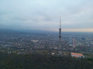 Obraz premium Koktobe TV tower on a hill at sunset, against the background of the city. Cloud cover. Autumn. The view from the drone.
