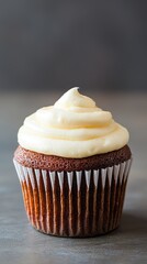 Delicious chocolate cupcake topped with creamy vanilla frosting on a grey background.