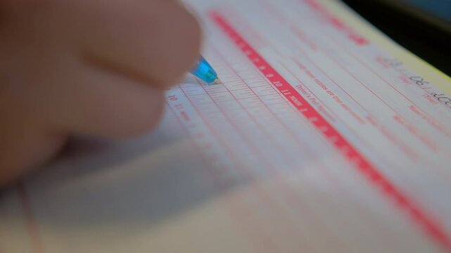 Filling out the log book card for a semi truck driver. Close up shot of pen