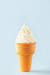 Vanilla soft ice cream ball in a waffle cone on a blue background