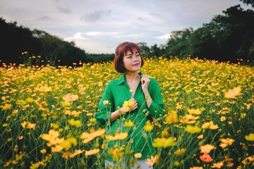 Fototapeta premium Woman Smiling in a Field of Yellow Cosmos Flowers