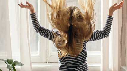 Little girl window shake healthy hair going looking at camera smiling child home happy kid funny...