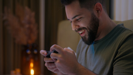 Excited Caucasian man playing mobile phone smartphone cellphone game gamer control emotional male...
