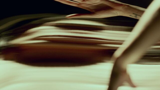 Young handsome long-haired man with shirtless torso performing enigmatic dance in dark room with distorting mirror, altering his reflection in surreal way