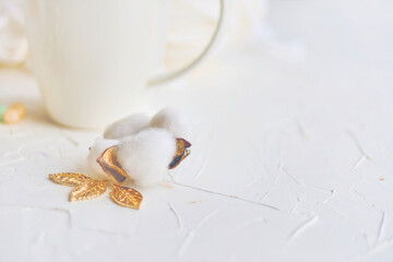 Serene atmosphere with white background, cotton flower, and golden leaves creates a refined setting