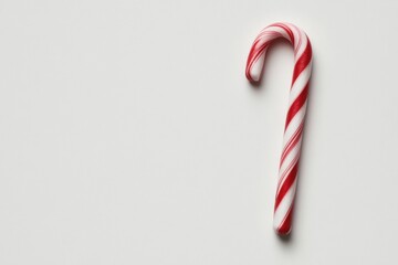 Christmas candy cane resting on a white background