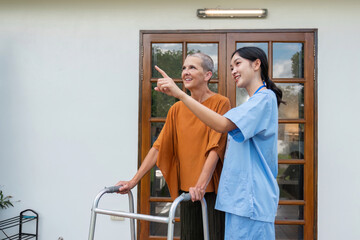 Naklejka premium Elderly Woman and Caregiver Enjoy a Walk in the Garden Outside Their Home on a Sunny Day