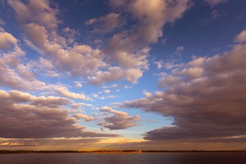 Obraz premium Sunset Sky Over Water with Golden Clouds