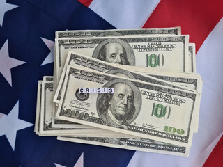 Stacked hundred dollar bills with the word crisis against an American flag 
