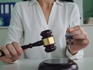 A legal professional uses a gavel to finalize a property transaction with house keys in hand during...