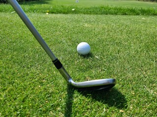 A close-up view of a golf club positioned beside a golf ball