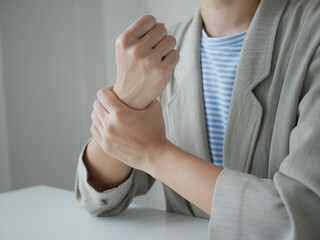 A young businesswoman has severe pain in her wrist. She has numbness. She massages her arm by...
