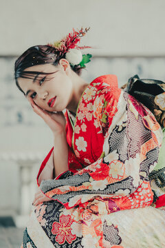 頬杖をつく赤い振袖の女性