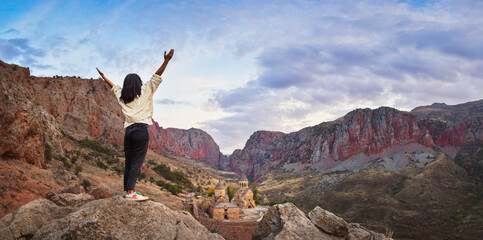 Excited happy tourist woman with outstretched arms admires the view of the famous Armenian...