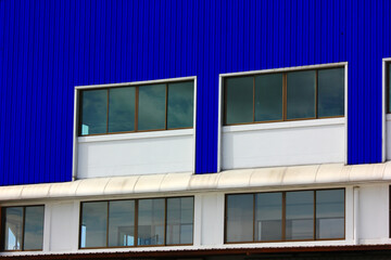 corrugated metal wall with windows on cement wall of factory warehouse  building