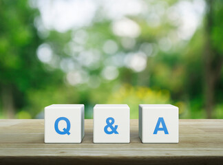 Q and A acronym on white block cubes on wooden table over blur green tree in park, Business...