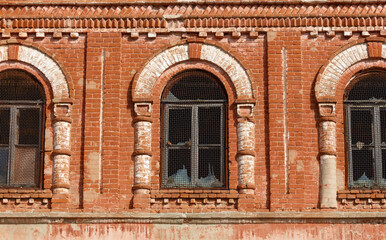 The brick building has three windows with arched tops