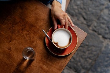 Woman with cup of coffee at wooden table, top view. Woman drinking fresh brewed coffee
