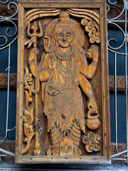 A wooden carving of a woman holding a staff and a pot