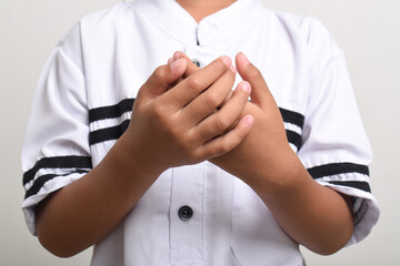 Close up Asian Muslim boy praying with open hands isolated on white background. Prayer gesture with raised hands