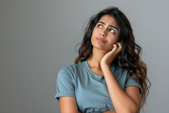 A young Indian female with a thinking face looking up