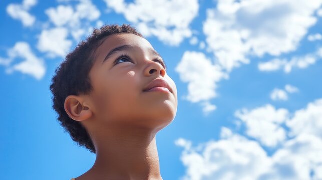A boy of mixed heritage looks upward possibly reflecting on the marvels of life or considering his dreams and ambitions