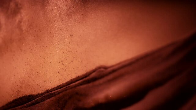 Abstract macro shot of sandy dust particles floating above the sand pile. 