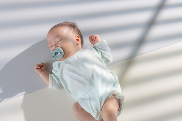 Asian newborn baby with pacifier and lying on the mat