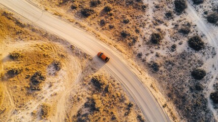 Fototapeta premium Aerial perspective of a vehicle on a winding road through a desert landscape